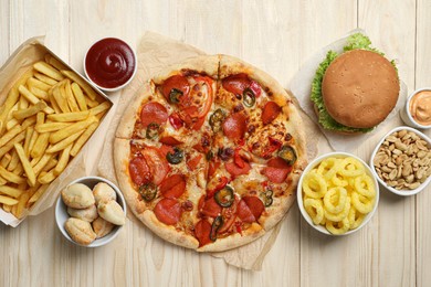 Pizza, onion rings and other fast food on wooden table, flat lay