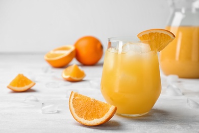 Photo of Glass of orange juice with ice cubes and cut fruit on table. Space for text