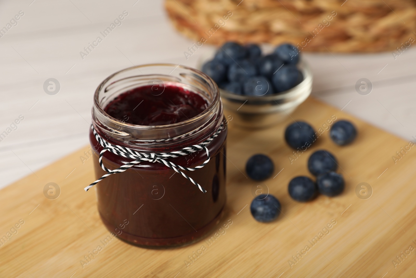 Photo of Jar with tasty blueberry jam and berries on wooden table. Space for text