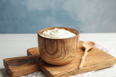 Photo of Wooden bowl with creamy yogurt served on table