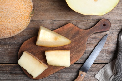 Photo of Delicious ripe melons and knife on wooden table, flat lay