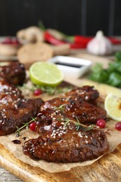 Photo of Tasty chicken wings glazed in soy sauce with garnish on wooden board, closeup