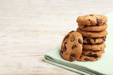 Photo of Stack of cookies with chocolate chips on wooden table, space for text