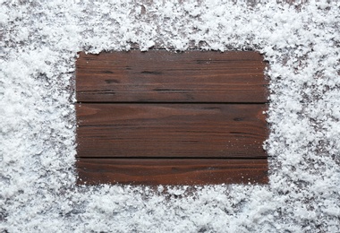 Photo of Frame made of snow on wooden background, top view with space for text. Winter season