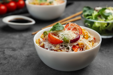 Photo of Tasty cooked rice noodles with vegetables on grey table