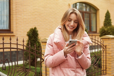 Photo of Beautiful young woman using mobile phone outdoors