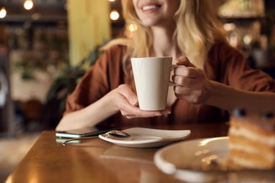 Photo of Young woman with cup of coffee at cafe in morning, closeup