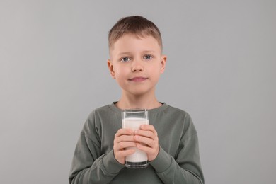 Photo of Cute boy with glass of fresh milk on light grey background