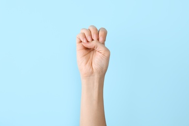 Photo of Woman showing E letter on color background, closeup. Sign language