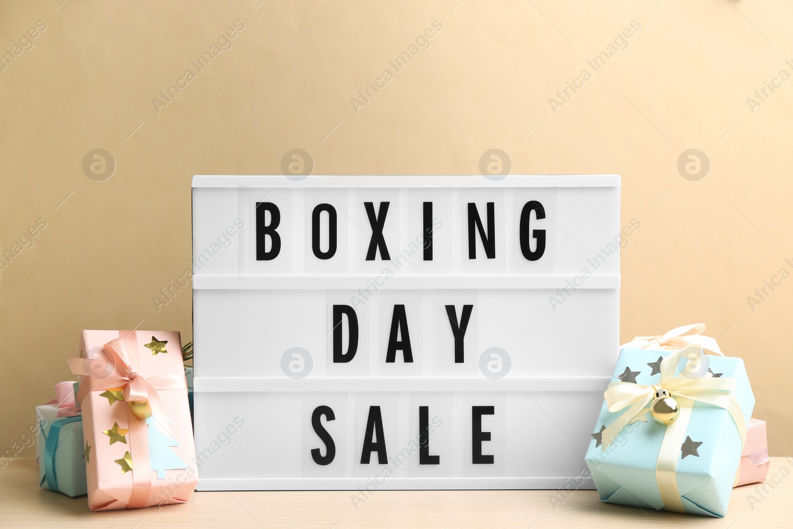 Photo of Composition with Boxing Day Sale sign and Christmas gifts on white table against beige background