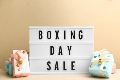 Photo of Composition with Boxing Day Sale sign and Christmas gifts on white table against beige background