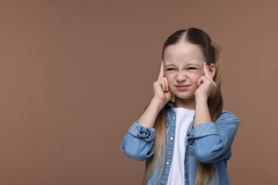 Photo of Little girl suffering from headache on brown background. Space for text