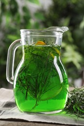 Photo of Jug of refreshing tarragon drink with lemon on table, closeup