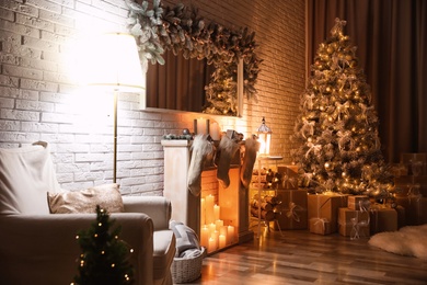 Photo of Stylish interior with beautiful Christmas tree and artificial fireplace at night