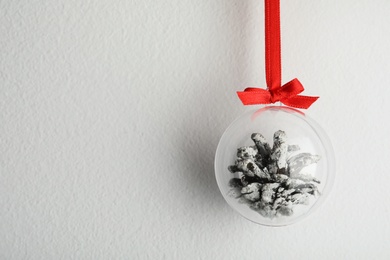 Photo of Decorative snow globe hanging on light grey background, space for text