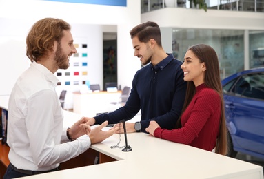 Photo of Car salesman and young couple in dealership