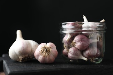Photo of Many fresh garlic bulbs on black board, closeup