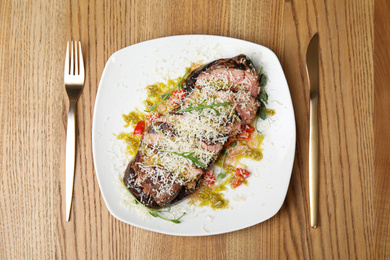 Photo of Delicious roasted meat served on wooden table, flat lay