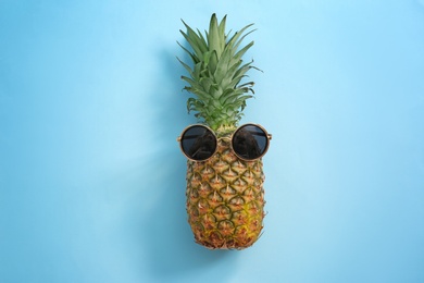 Photo of Fresh ripe pineapple with sunglasses on color background, top view