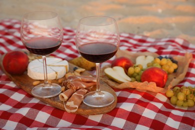 Photo of Blanket with wine and snacks for picnic on sandy beach