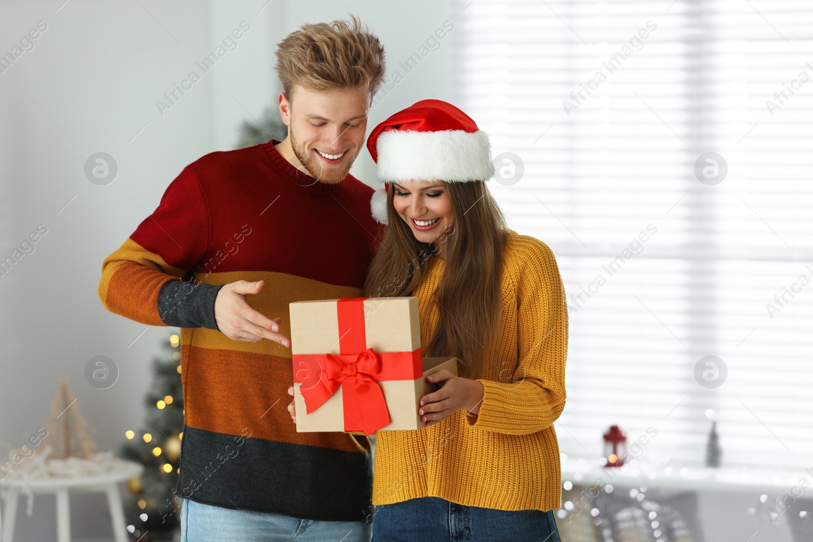 Photo of Happy young couple opening Christmas gift at home