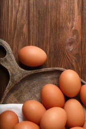 Photo of Raw brown chicken eggs on wooden table, flat lay. Space for text