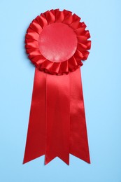 Photo of Red award ribbon on turquoise background, top view