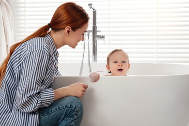 Photo of Mother washing her little baby in tub at home
