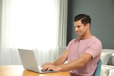 Photo of Man using laptop for search at wooden table in living room
