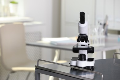 Photo of Modern medical microscope on metal table in laboratory, space for text