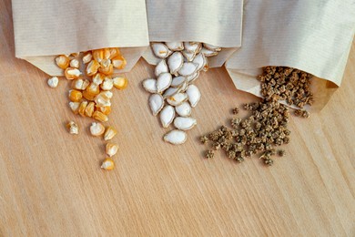 Photo of Different vegetable seeds on wooden table, flat lay