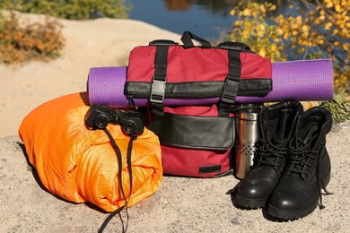 Photo of Set of camping equipment with sleeping bag on ground outdoors