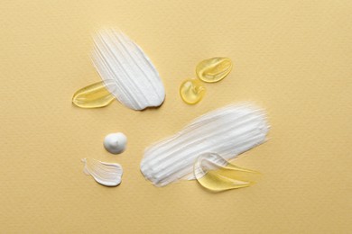 Photo of Samples of transparent gel and white cream on yellow background, flat lay
