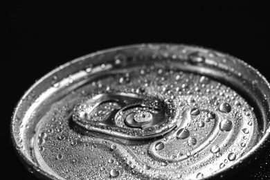 Photo of Aluminum can of beverage covered with water drops on black background, closeup