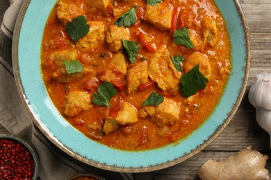 Photo of Delicious chicken curry and ingredients on wooden table, top view