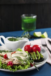 Photo of Tasty mozzarella, chicken and vegetables with tarragon served on blue table, closeup