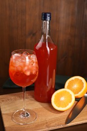 Photo of Aperol spritz cocktail and ice cubes in glass and bottle on wooden table