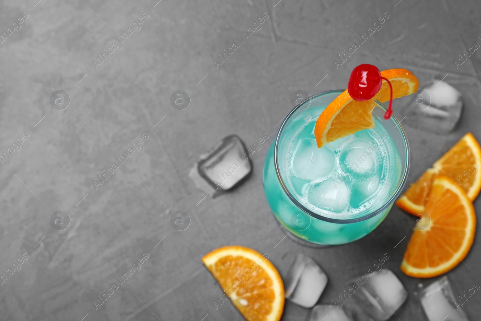 Photo of Glass of tasty refreshing cocktail on grey stone background, flat lay. Space for text