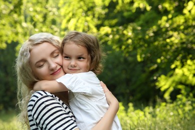 Photo of Beautiful mother with her cute daughter spending time together outdoors, space for text