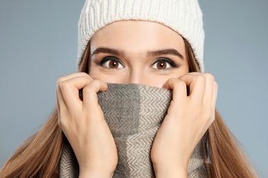 Photo of Happy young woman in warm clothes on grey background, closeup. Winter season