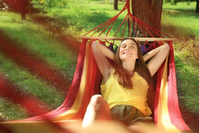 Photo of Young woman resting in comfortable hammock at green garden