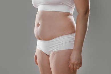 Photo of Woman with excessive belly fat on grey background, closeup. Overweight problem