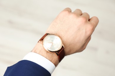 Photo of Businessman with luxury wrist watch on blurred background, closeup