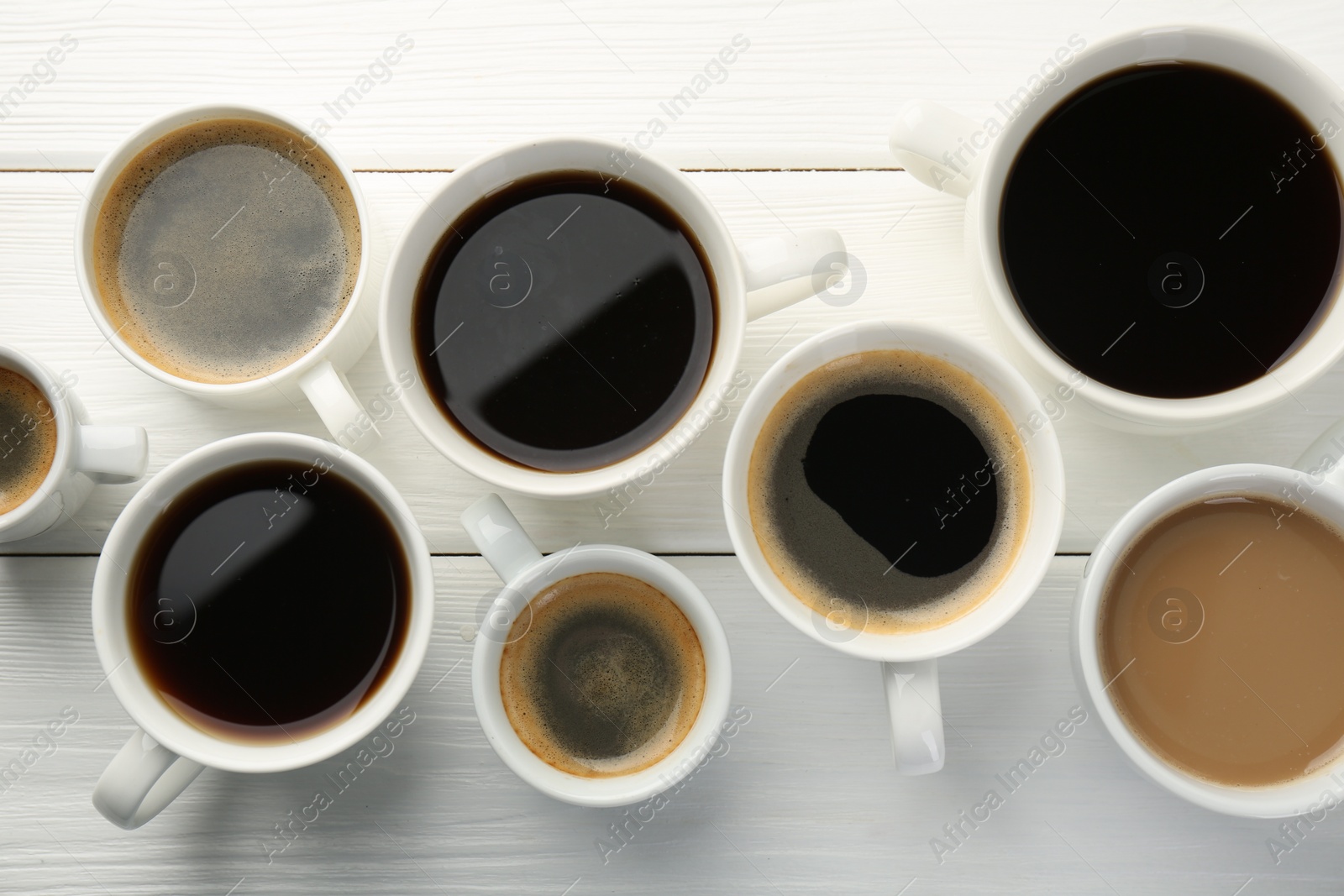 Photo of Different coffee drinks in cups on white wooden table, flat lay