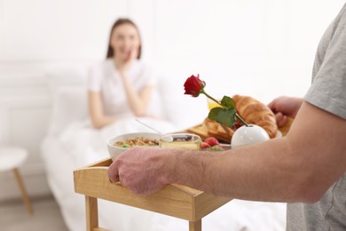Romantic breakfast. Husband bringing tray with tasty food to his wife in bedroom, closeup. Space for text