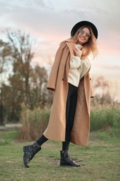Photo of Beautiful young woman wearing stylish autumn clothes outdoors