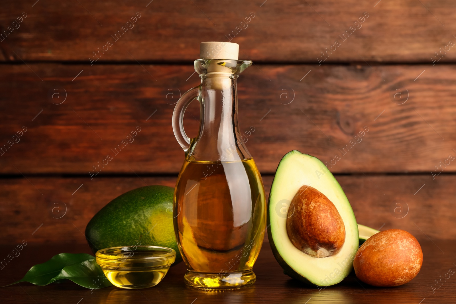 Photo of Cooking oil and fresh ripe avocados on wooden table