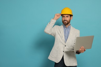 Photo of Professional engineer in hard hat with laptop on light blue background, space for text