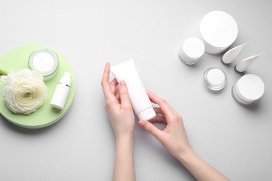 Photo of Woman holding tube of cream on light background, top view