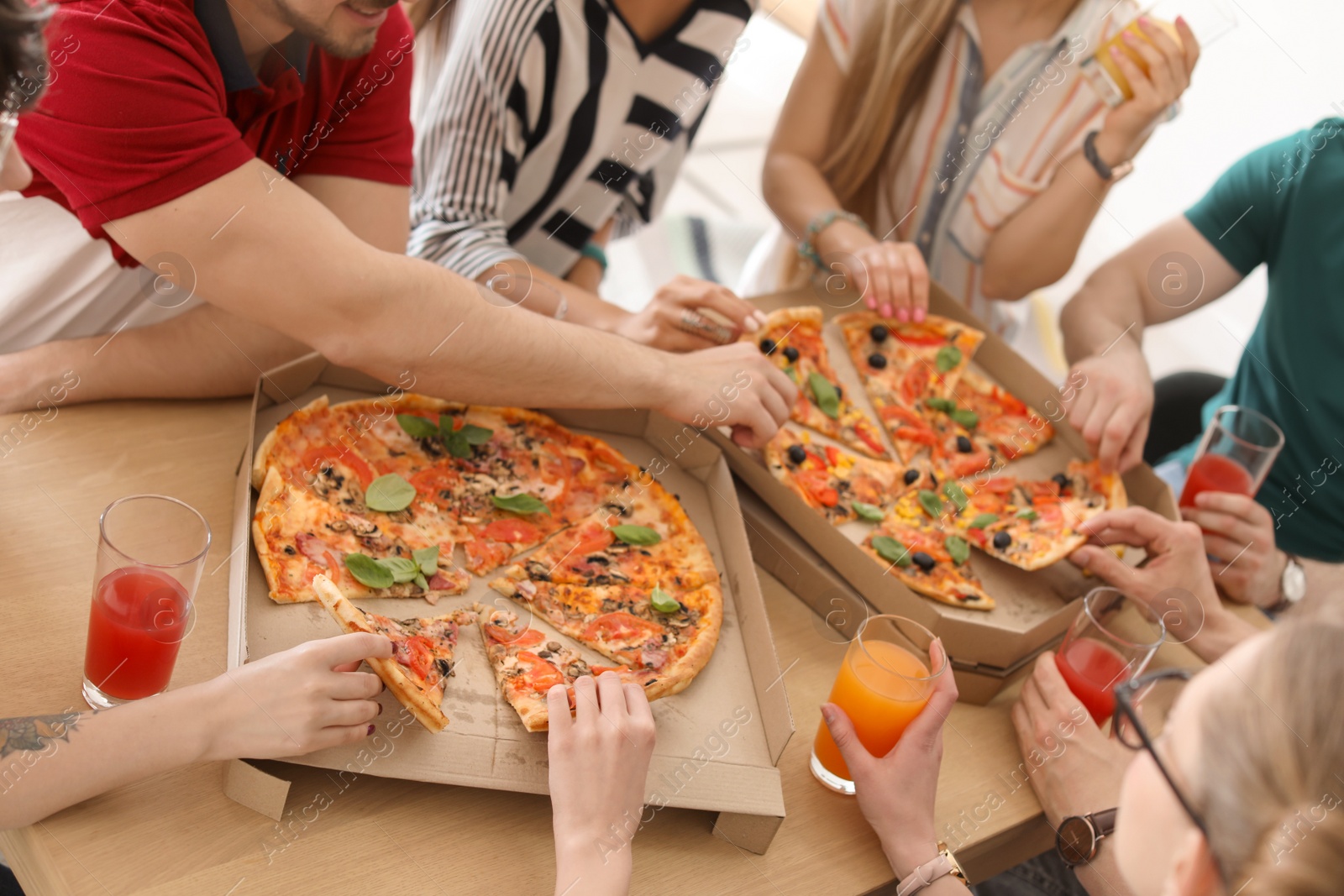 Photo of Young people eating delicious pizzas at table, closeup